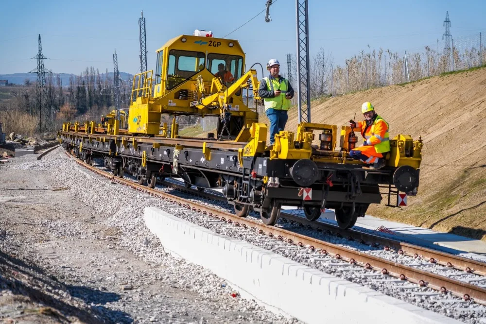 Delovni vlak na drugem tiru, na njem sta dva delavca.