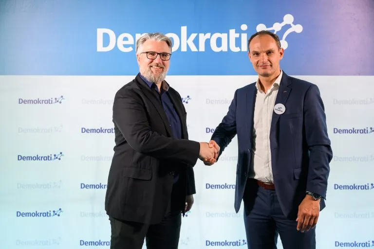 Janez Demšar in Anže Logar se rokujeta, za njima napis Demokrati.